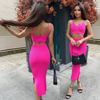Woman in a bright pink outfit standing outdoors with a black handbag.