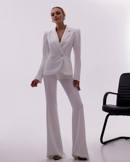 Woman wearing a white suit standing next to a black office chair on a white background
