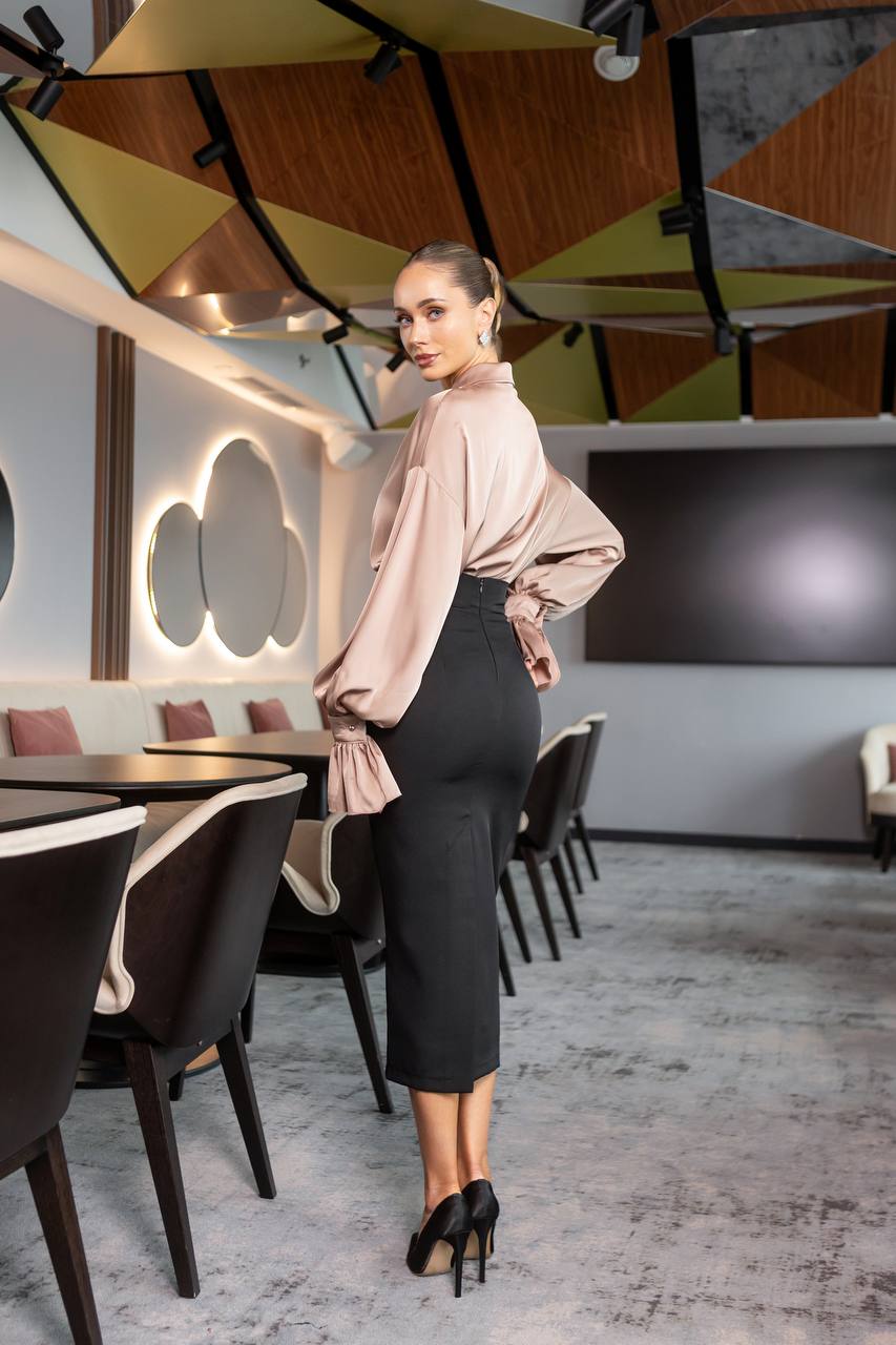 Woman in a stylish outfit standing in a modern restaurant with geometric ceiling design.