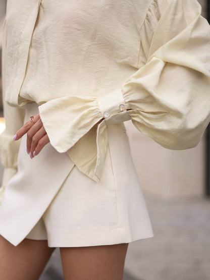 Person wearing a light-colored outfit with a bow detail on a blurred background