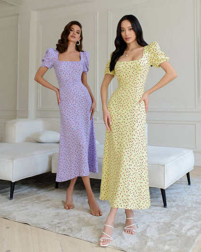 Two women wearing floral dresses in a room with white walls and furniture.