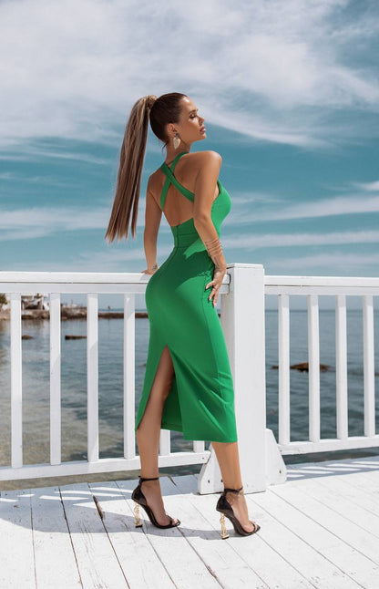 Woman in a green dress standing on a dock with water and sky in the background
