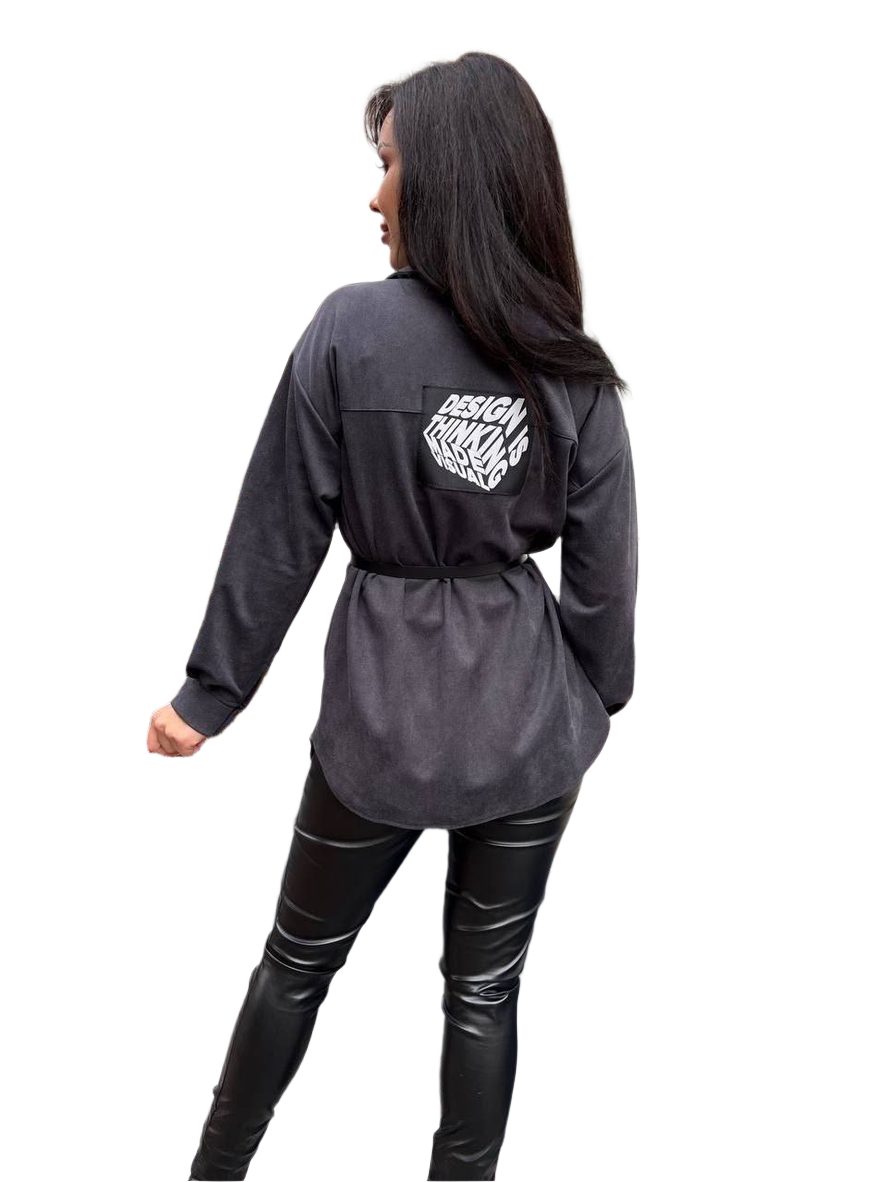 Person wearing a dark gray long-sleeve shirt with a logo on the back, standing against a white background.