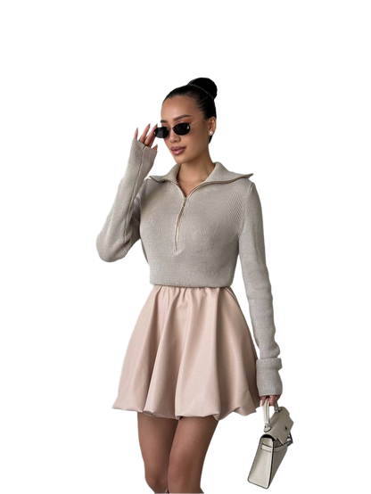 Woman wearing a beige sweater and skirt with sunglasses on a white background