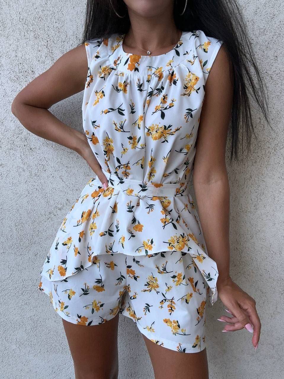 Woman wearing a white floral romper against a neutral background
