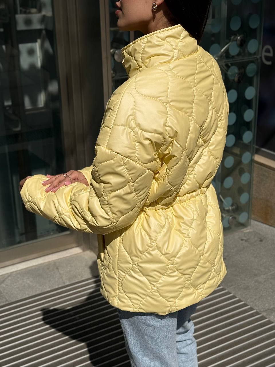Person wearing a yellow quilted jacket in an urban setting