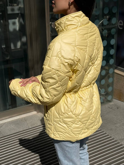 Person wearing a yellow quilted jacket in an urban setting