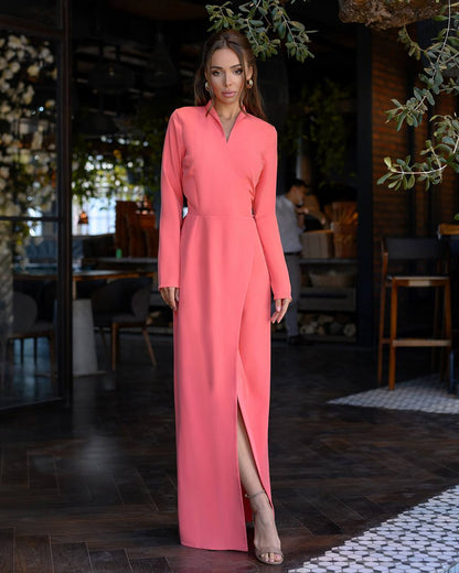 Woman wearing a long pink dress in an indoor setting with plants and furniture.