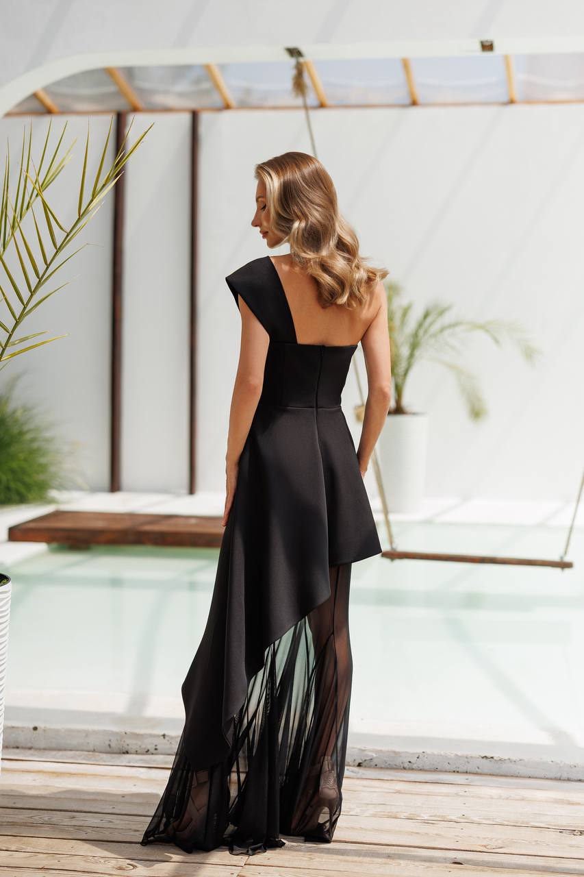 Woman wearing a black dress with sheer panels by a poolside.