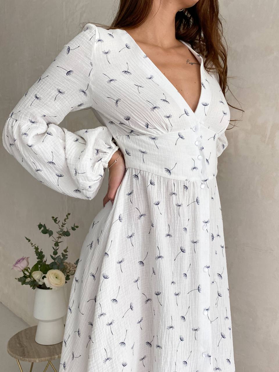 Woman wearing a white dress with a floral pattern against a neutral background