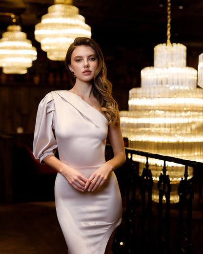Woman in a white dress standing in a dimly lit room with large chandeliers.