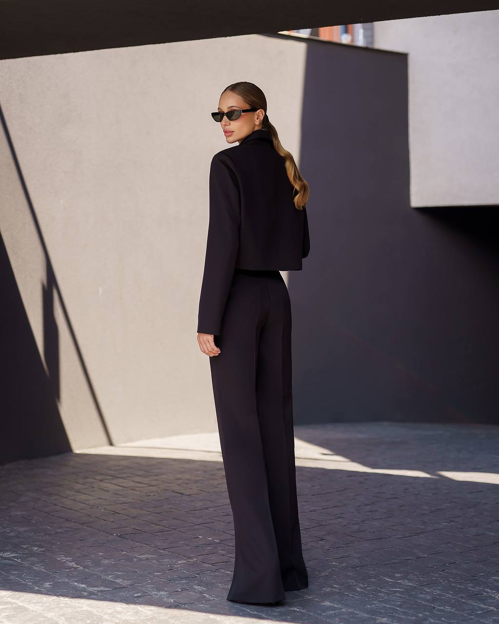 Woman in a black outfit standing in a modern architectural setting