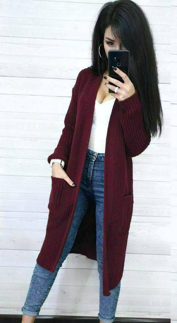 Person wearing a burgundy cardigan, white top, and blue jeans against a white background