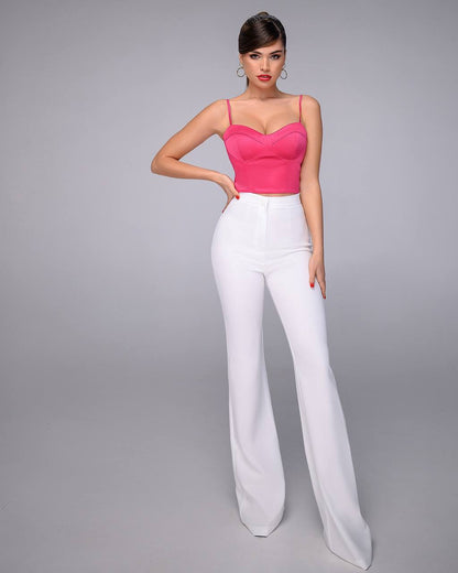 Woman wearing a pink top and white pants on a gray background