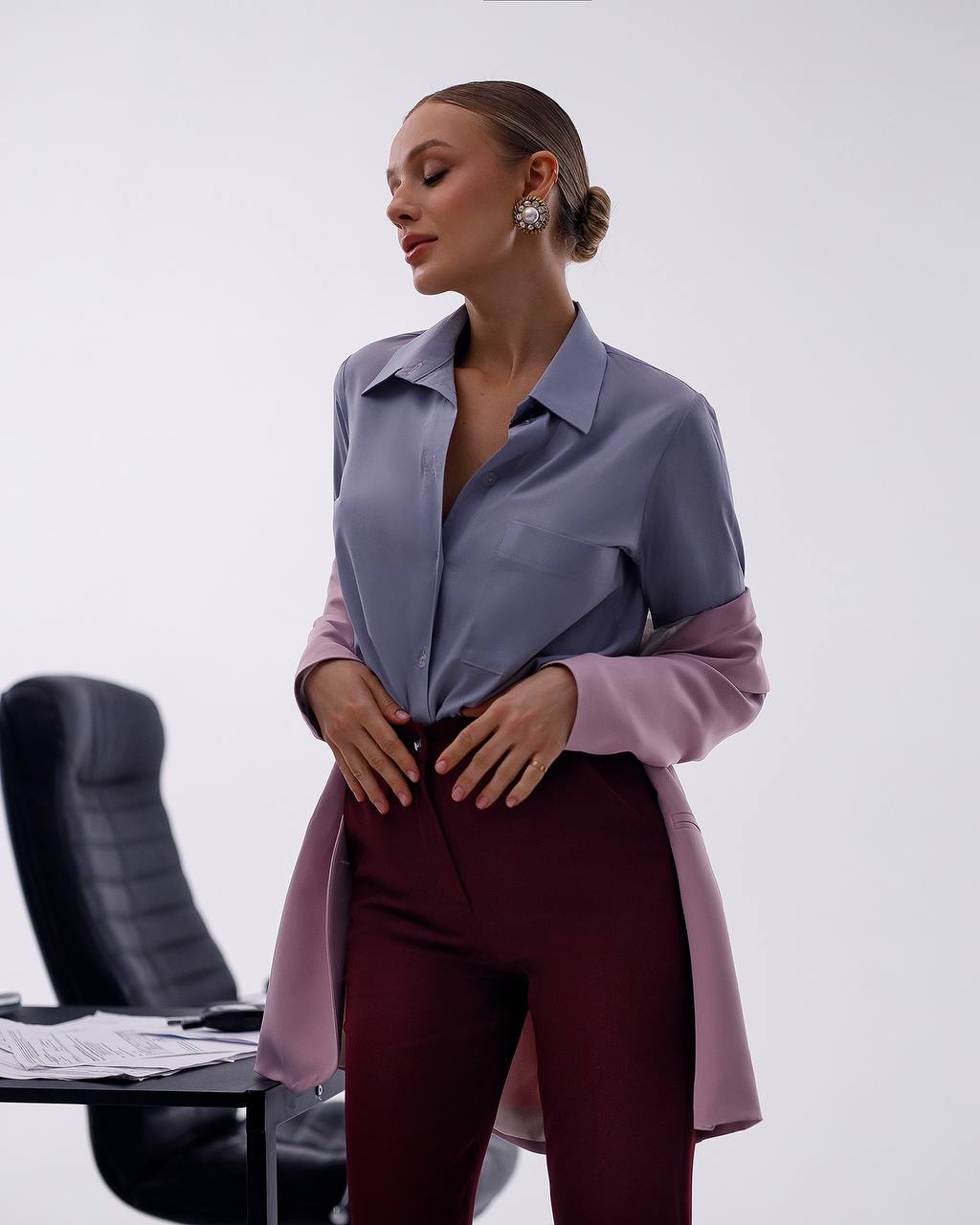 Woman wearing a long, light purple shirt over a burgundy outfit with a white background