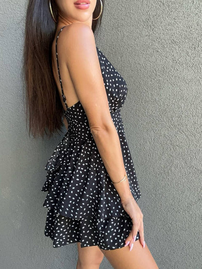 Woman wearing a black polka dot dress against a gray wall