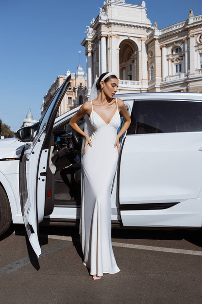 Woman in a white dress exiting a white limousine with a historic building in the background