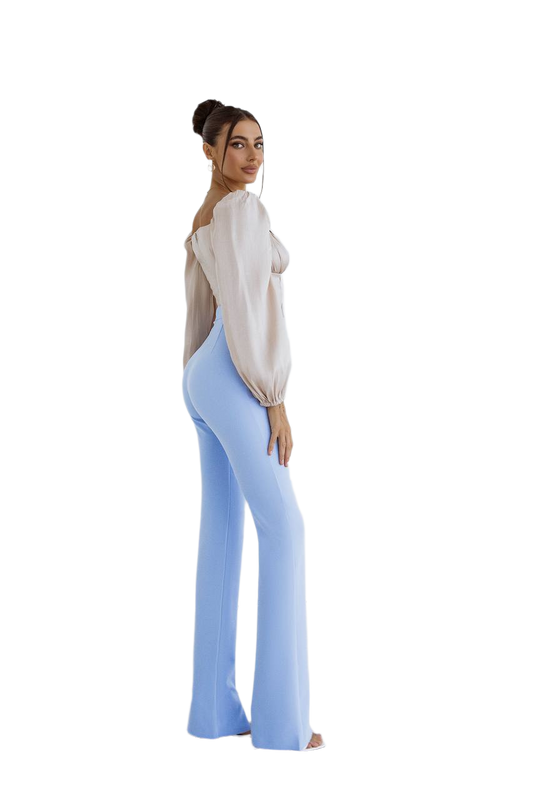 Woman wearing a white blouse and light blue flared pants on a white background