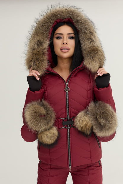 Woman wearing a red winter coat with fur hood and cuffs on a white background