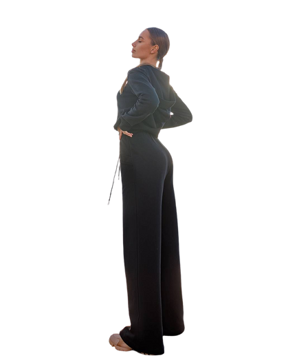 Woman wearing a dark green top and black pants on a white background