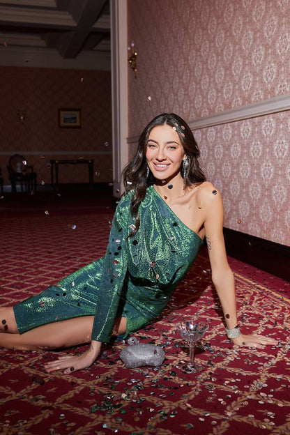 Woman in a green dress posing on a red carpet with confetti