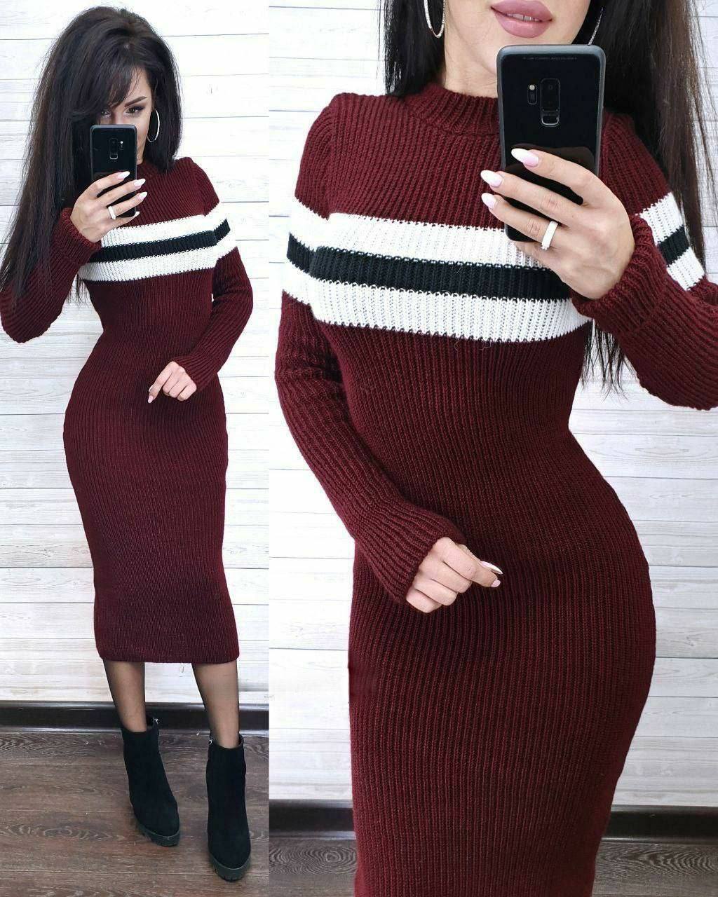 Woman wearing a burgundy sweater dress with white and black stripes, taking a mirror selfie.