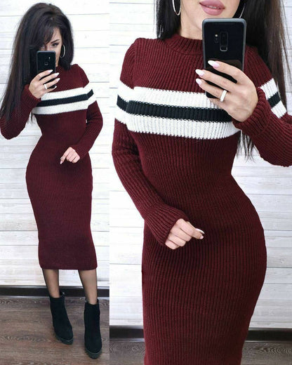 Woman wearing a burgundy sweater dress with white and black stripes, taking a mirror selfie.