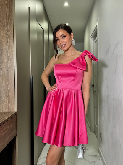 Woman in a pink one-shoulder dress standing in a hallway.