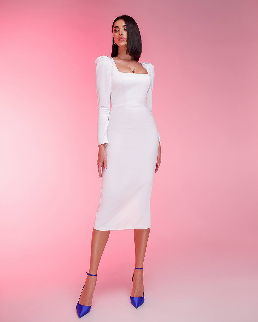 Woman wearing a white dress with long sleeves against a pink background