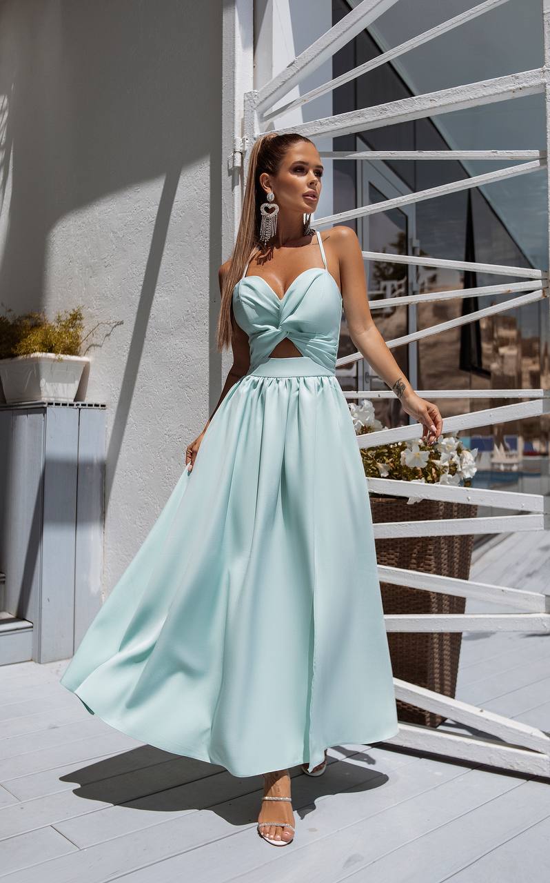 Woman in a light blue dress standing on a balcony with a white railing.