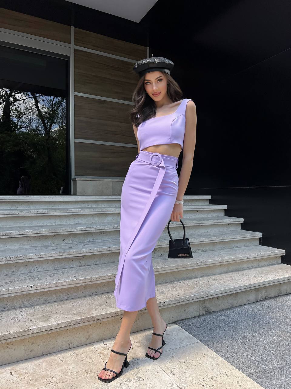 Woman in a lavender outfit standing on steps outside a modern building