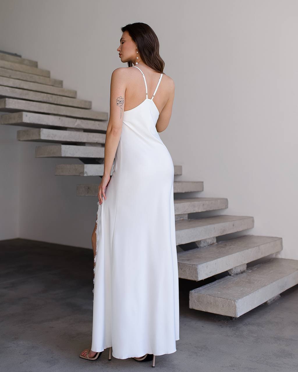 Woman in a white dress standing in front of concrete stairs