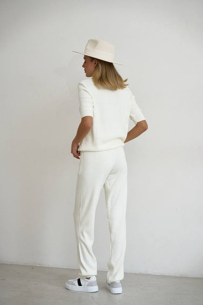 Person wearing a white outfit with a hat against a plain background