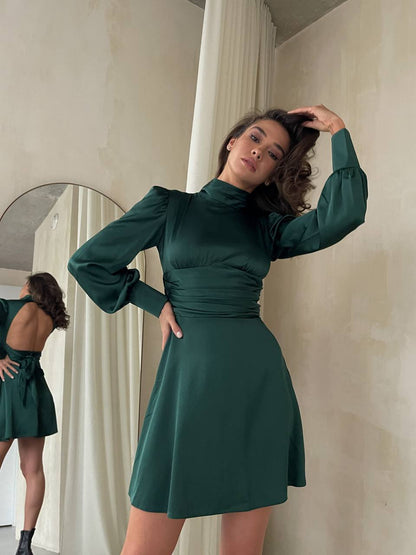 Woman wearing a green dress standing in front of a mirror.