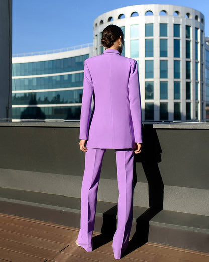 Person wearing a purple suit standing on a rooftop with modern buildings in the background