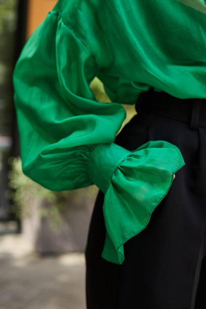Green blouse with a large bow detail on a blurred background