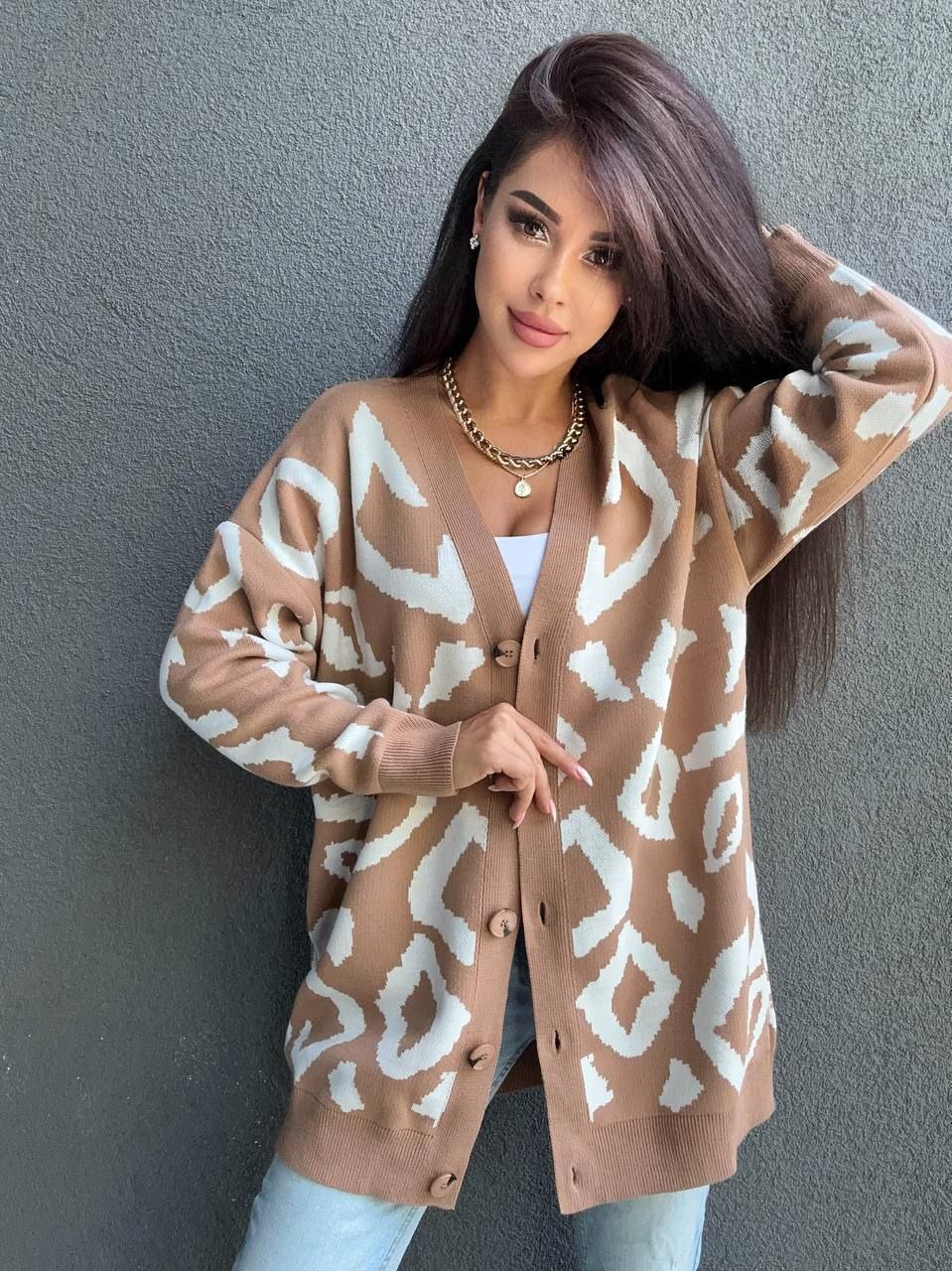 Woman wearing a beige cardigan with white abstract pattern against a gray background