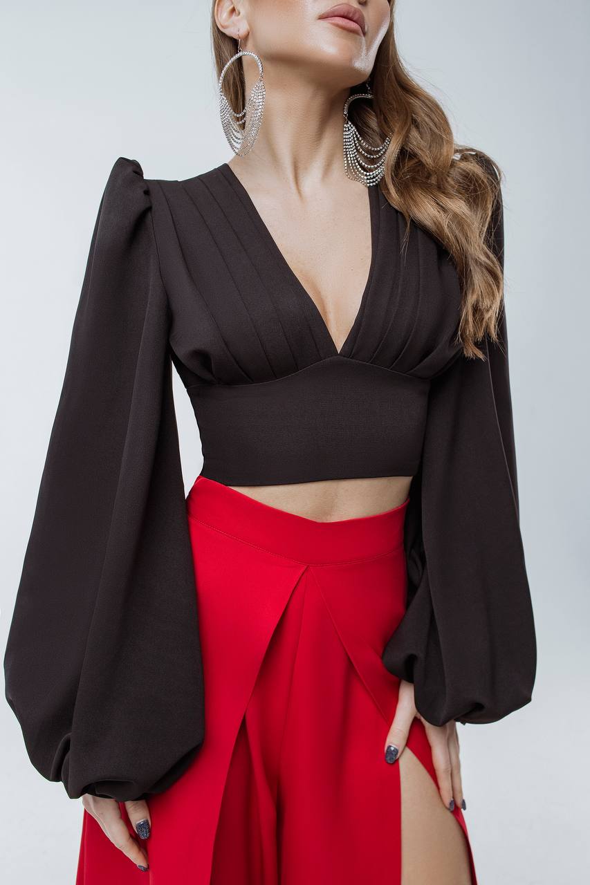 Woman wearing a black top and red skirt with a plain background