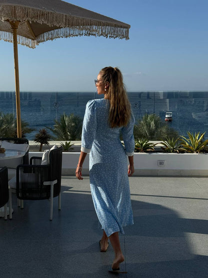 Woman in a blue dress standing on a rooftop with ocean view