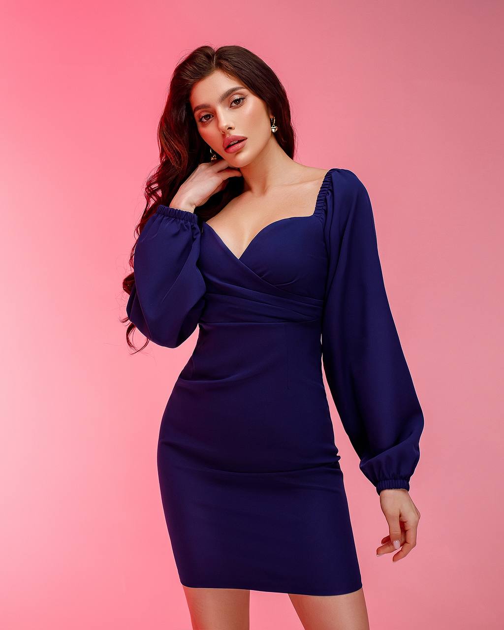 Woman wearing a blue dress against a pink background