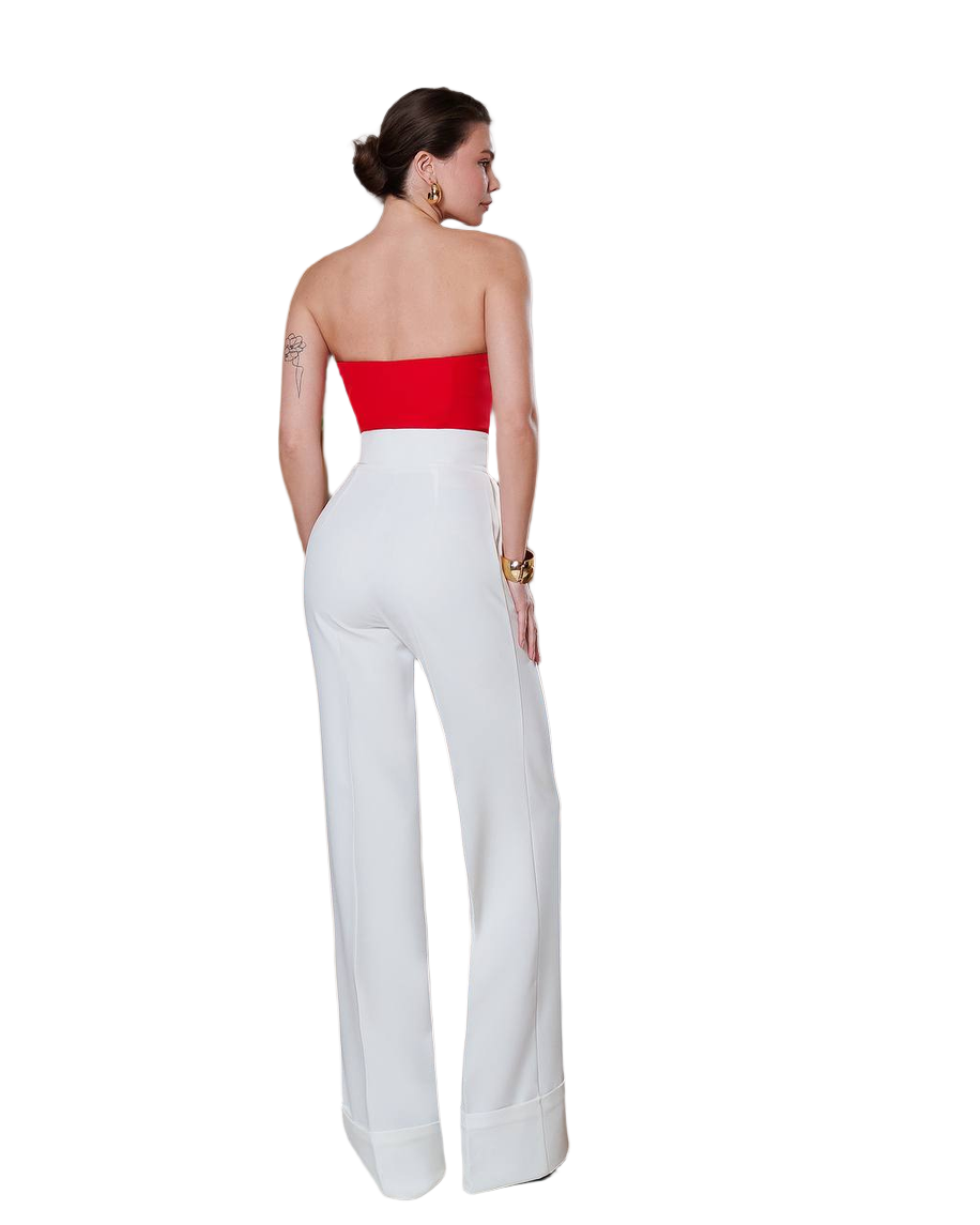 Woman wearing a strapless red top and white pants on a white background