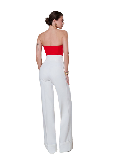 Woman wearing a strapless red top and white pants on a white background