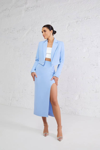 Woman wearing a light blue suit with a white top against a white background