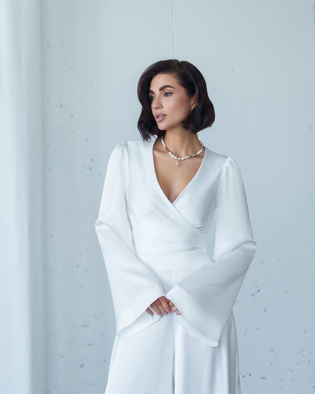 Woman wearing a white dress against a light gray background