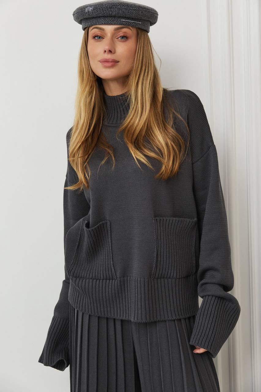 Woman wearing a dark gray sweater and cap against a white background