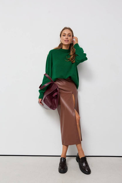 Woman wearing a green sweater and brown leather skirt against a white background