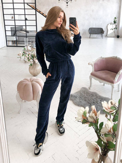 Woman taking a mirror selfie wearing a navy tracksuit in a stylish room.