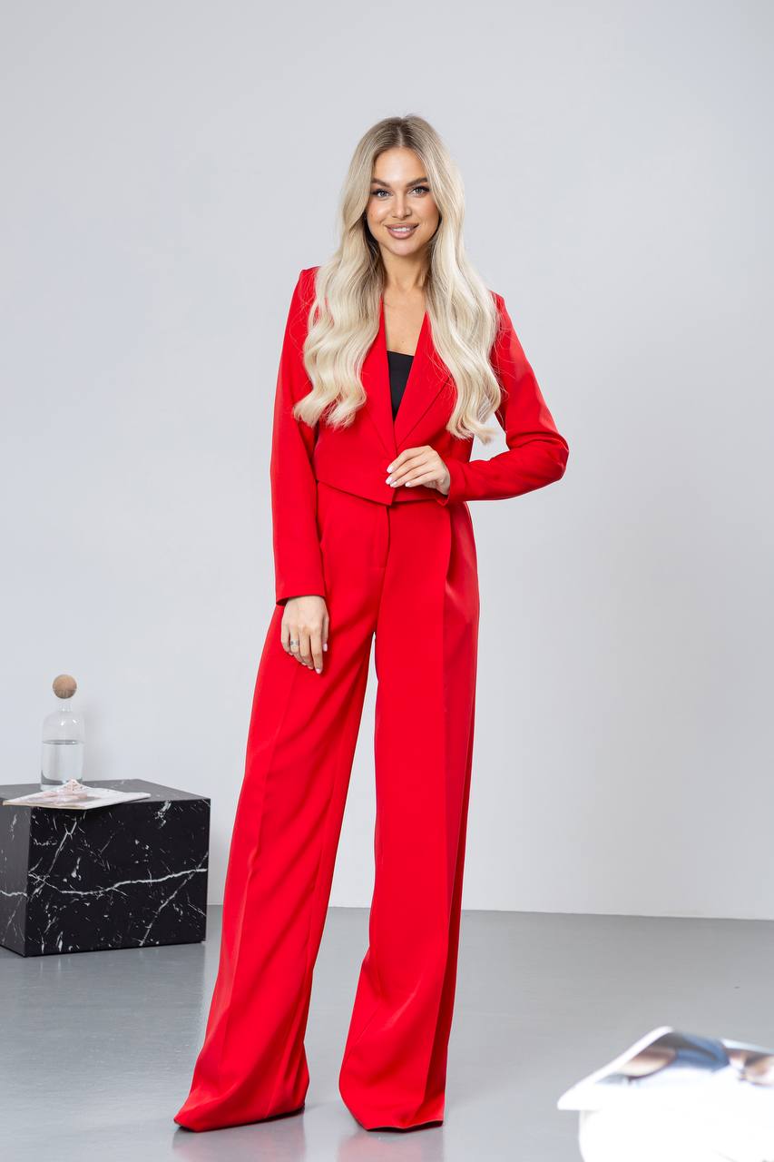 Woman wearing a red suit standing against a white background