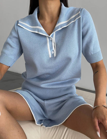 Person wearing a light blue outfit with white trim sitting on a couch.