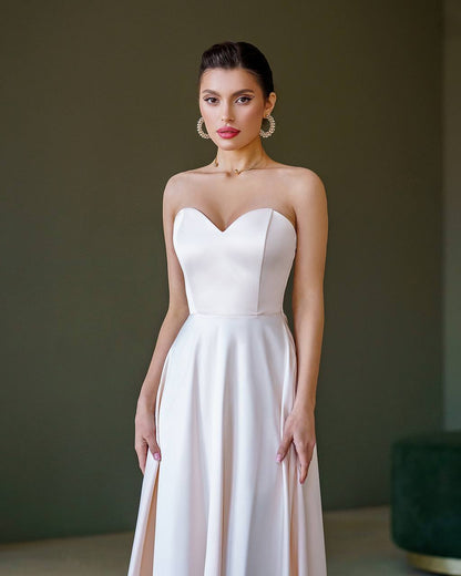 Woman wearing a strapless white dress against a dark background